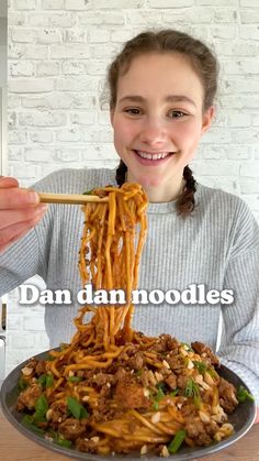 a girl is eating noodles with chopsticks in front of her face and the caption reads dan dan noodles