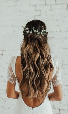 the back of a woman's head with long hair and flowers in her hair