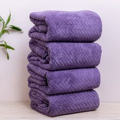 a stack of purple towels sitting next to a plant