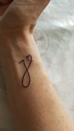 a person with a tattoo on their wrist holding up the letter j to symbolize love