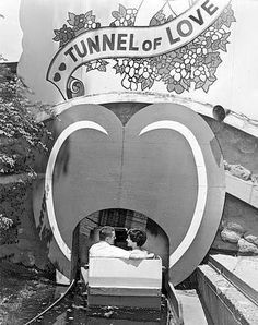 a man and woman sitting in front of a tunnel of love sign