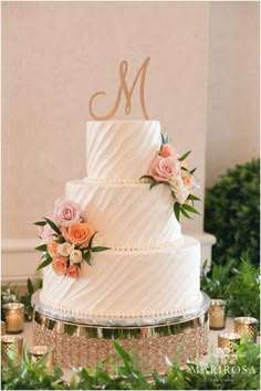 a wedding cake with flowers on top and the letter m on it's side