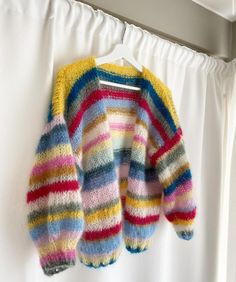 a colorful sweater hanging on a white curtain