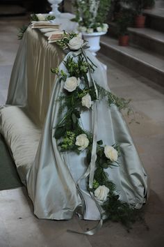 the bride's dress is covered with flowers and greenery on the side of the aisle