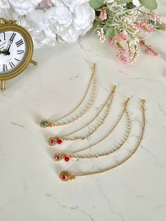 a bunch of necklaces sitting on top of a table next to a clock and flowers