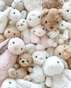 a pile of stuffed animals sitting next to each other on top of a floor covered in white and pink