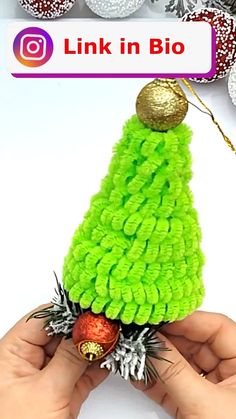 a hand holding a small green christmas tree ornament