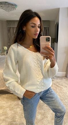 a woman is taking a selfie in her bedroom while wearing jeans and a sweater