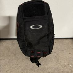 a black backpack sitting on the floor in front of a wall with an eye drawn on it