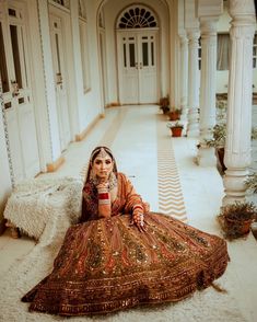 a woman is sitting on the floor in an ornate dress and holding a coffee cup