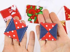 two hands holding small red, white and blue pieces of fabric with polka dots on them