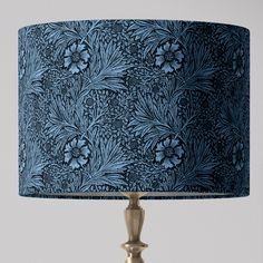 a blue and gold lamp on a white table with a black lampshade over it