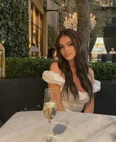 a woman sitting at a table with a glass of wine