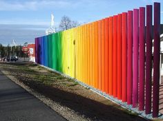 a rainbow colored fence is next to a street