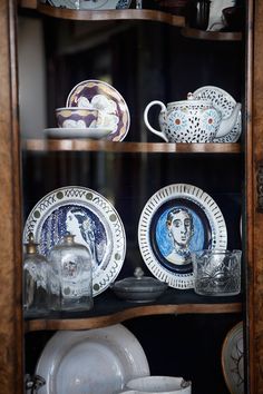 an old china cabinet with plates and dishes on it