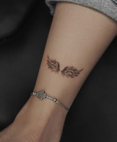 a woman's arm with an angel wing tattoo on the left side of her wrist