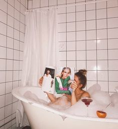 two women sitting in a bathtub reading books