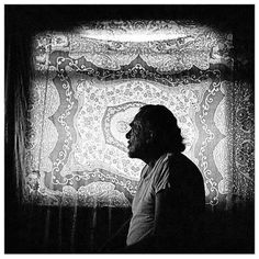 a man standing in front of a window next to a wall with an intricate design on it