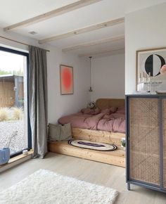 a bedroom with a bed, dresser and window in the corner that looks out onto the yard