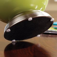 a green and black object sitting on top of a wooden table next to a cell phone