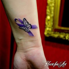 a purple ribbon with a butterfly tattoo on the left side of the wrist is shown in front of a mirror