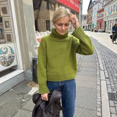 a woman is walking down the street with her hand on her head while holding a bag