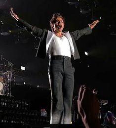 a man standing on top of a stage holding his arms out