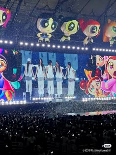 a group of people standing on top of a stage in front of a large screen