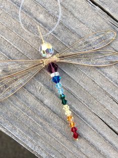 a dragonfly ornament is hanging on a wooden table with beads and chains