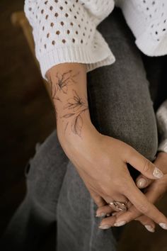 a woman's hand with a flower tattoo on her left arm and right hand