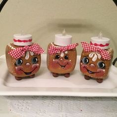 three little jars with faces painted on them sitting on a white tray next to each other