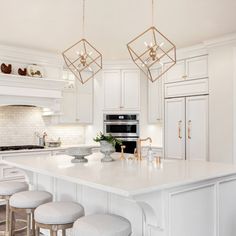 a large kitchen with white cabinets and marble counter tops, an island with stools