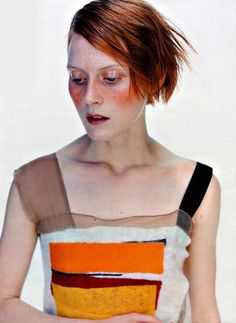 a woman with red hair is looking down at her cell phone while wearing an orange and brown dress