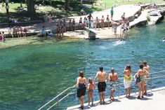 several people are standing on the edge of a dock