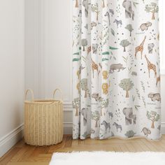 the curtains in this room are decorated with animals and trees on white fabric, along with a wicker basket for storage