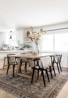 a dining room table with four chairs and a rug on the floor in front of it