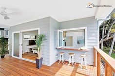 an outdoor living area with wooden floors and white walls, including a balcony overlooking the backyard