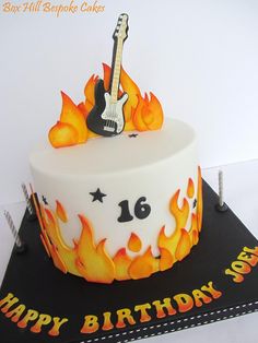 a birthday cake with a guitar on top and flames around the edges that reads, happy 16th birthday