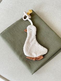 a white towel with a duck on it hanging from the side of a bed next to a pair of scissors