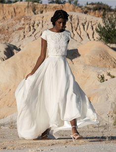 a woman in a white dress is walking through the desert with her hand on her hip