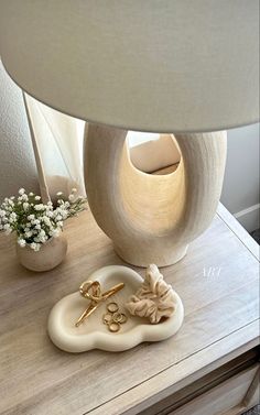 a white lamp sitting on top of a wooden table next to a vase with flowers