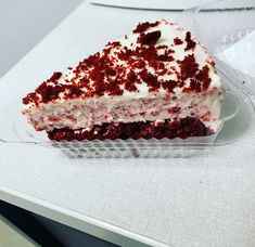 a piece of cake sitting on top of a plastic container filled with red and white frosting