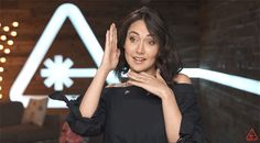 a woman standing in front of a sign with her hand up to her face and wearing a black dress