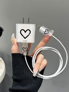 a woman is holding an electric device with hearts on it and plugged into the charger