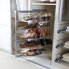 several pairs of shoes are stored in a metal shoe rack on the floor next to an open closet door