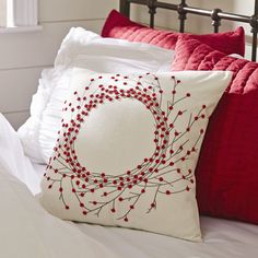 a white bed topped with red pillows and blankets