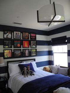 a bedroom decorated in blue and white stripes with pictures on the wall above the bed