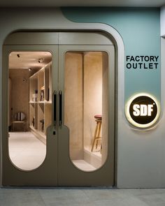 an entrance to a factory outlet with glass doors and illuminated sign on the wall that reads sdf