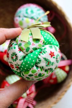 a hand is holding an ornament with green and red designs on it in a basket