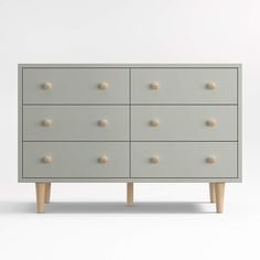 a grey dresser with wooden legs and knobs on it's drawers, against a white background